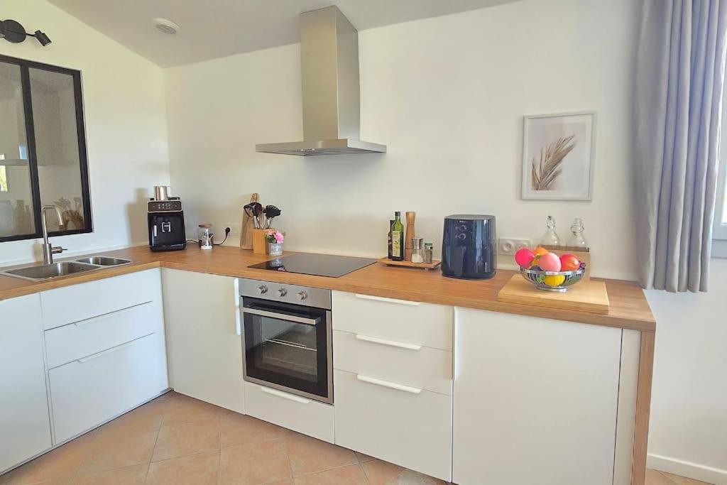 une cuisine avec des armoires blanches et un comptoir en bois dans l'établissement Domaine des Lions - Logement chaleureux climatisé à Sérignan, à Sérignan