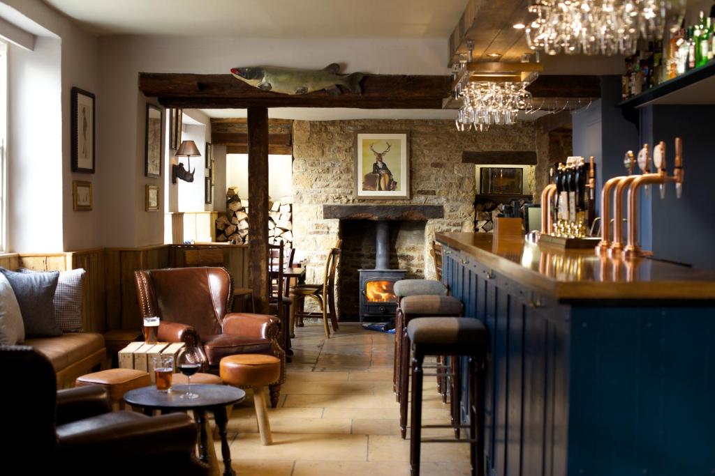 a bar in a pub with chairs and a fireplace at The Trout at Tadpole Bridge in Faringdon