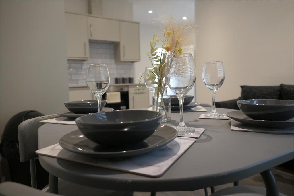 a table with bowls and plates and wine glasses at Exclusive London Apartment - Wembley Stadium, OVO Wembley Arena in London