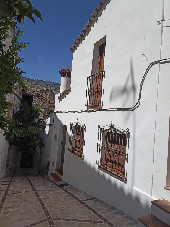 a white building with two windows on the side of it at Casa Alameda in Benarrabá