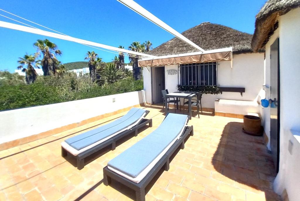 a patio with chaise lounges and a table at Mandala Bungalows - Adults Only in Los Caños de Meca