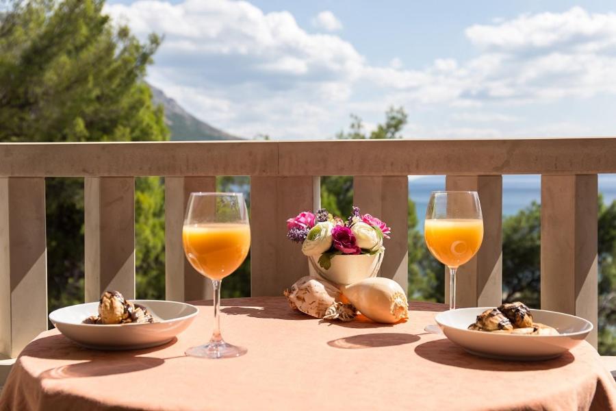 a table with two glasses of orange juice and food at Villa Nada in Duće
