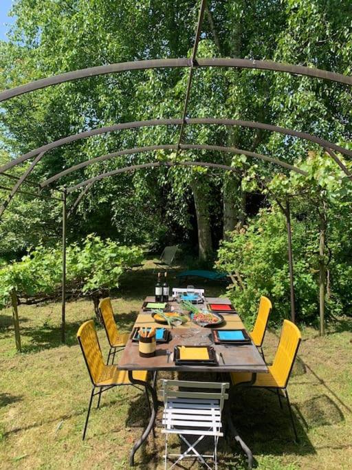 une table en bois avec des chaises sous une tonnelle dans l'établissement Grande longère normande, à Doudeville