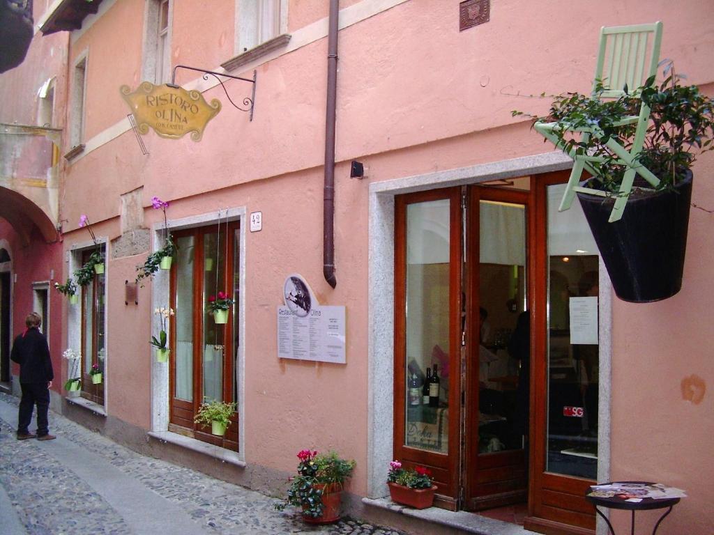una persona caminando por una calle al lado de un edificio rosa en Piccolo Hotel Olina, en Orta San Giulio