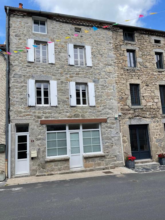 un grande edificio in pietra con finestre e bandiere bianche di MAISON DE VILLAGE a Chambon-le-Château