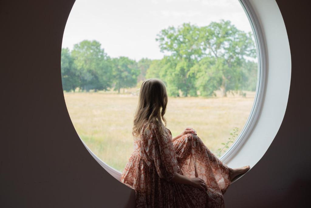 una donna che guarda fuori da una finestra rotonda di loft-feeling im Cottage! a Brandenburg an der Havel