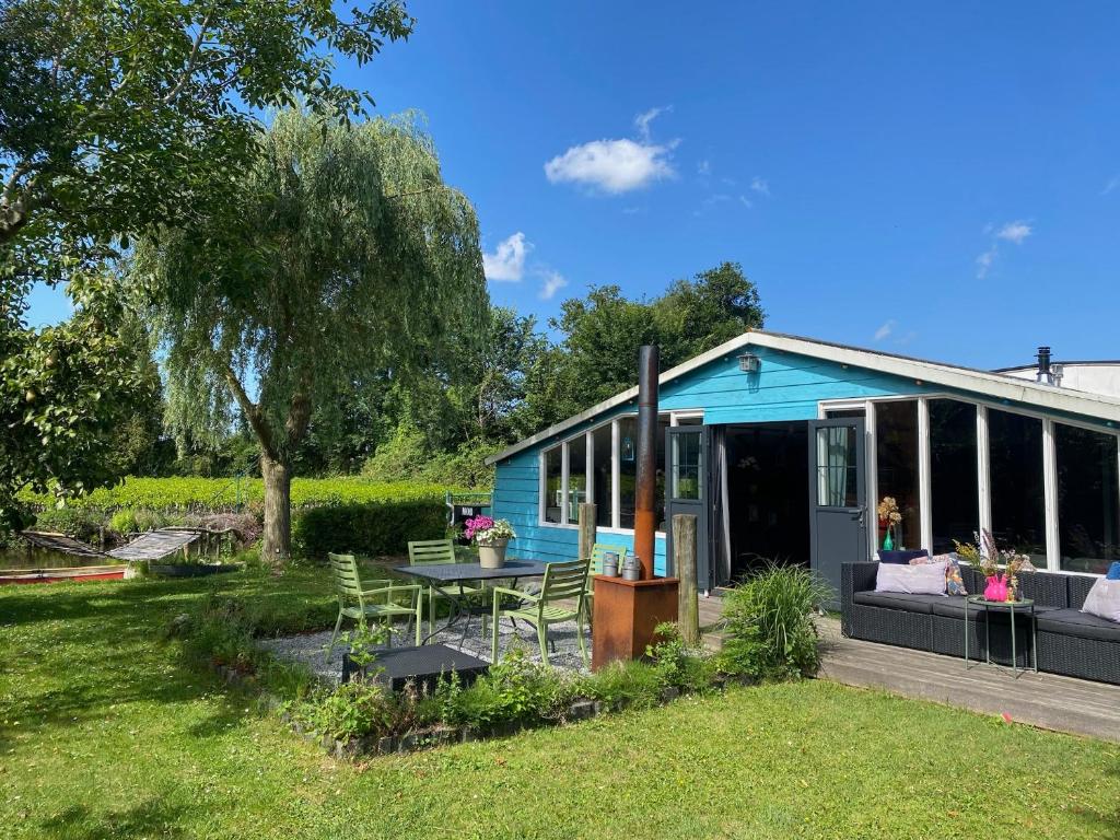 a blue house with a table and chairs in the yard at Beautiful house on an island near Amsterdam in Oude Meer