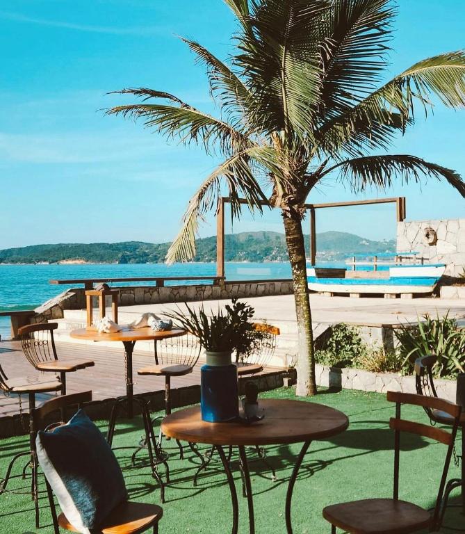 a patio with tables and chairs and a palm tree at Casa pe na areia em Buzios in Búzios