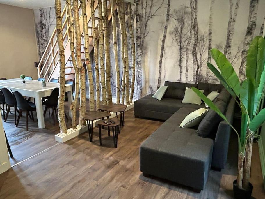 - un salon avec un canapé, une table et des arbres dans l'établissement Natur 'Appart entre forêt et rivière, à LʼHuisserie