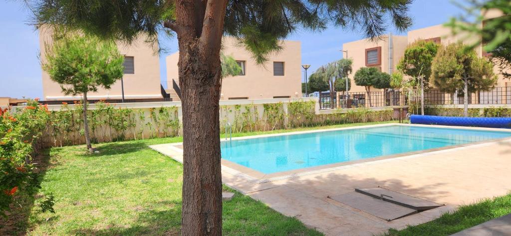 a swimming pool in a yard with a tree at Appartement luxe Taghazout bay - mer & piscine in Agadir