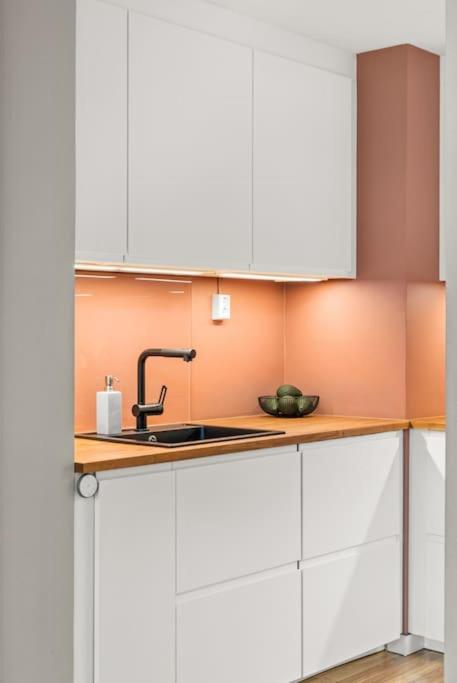 a kitchen with white cabinets and a sink at Sentral & Cozy apartment in Oslo