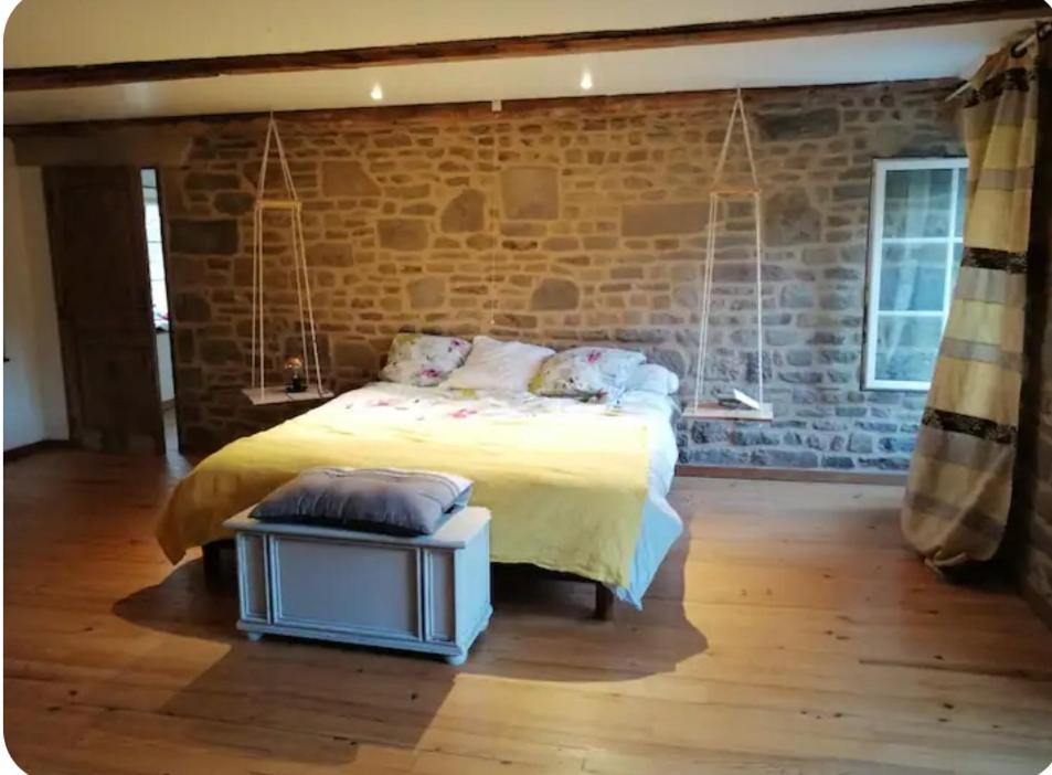 une chambre avec un lit et un mur de briques dans l'établissement Havre de paix, à La Bloutière