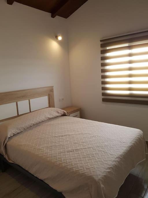 a bedroom with a white bed and a window at Casa Alejandra en el palmar in Cádiz
