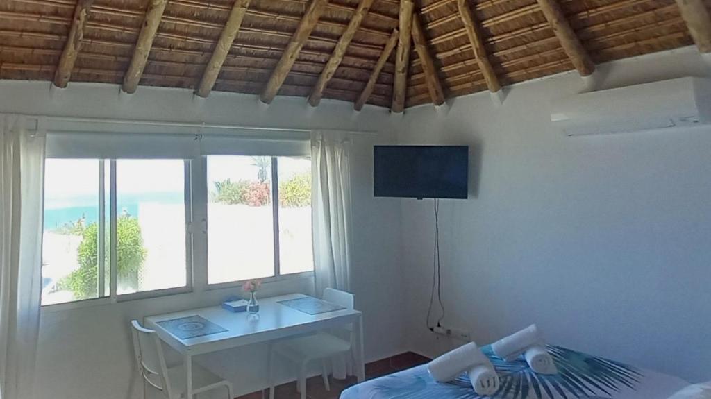 a room with a bed and a table and a television at Mandala Bungalows - Adults Only in Los Caños de Meca