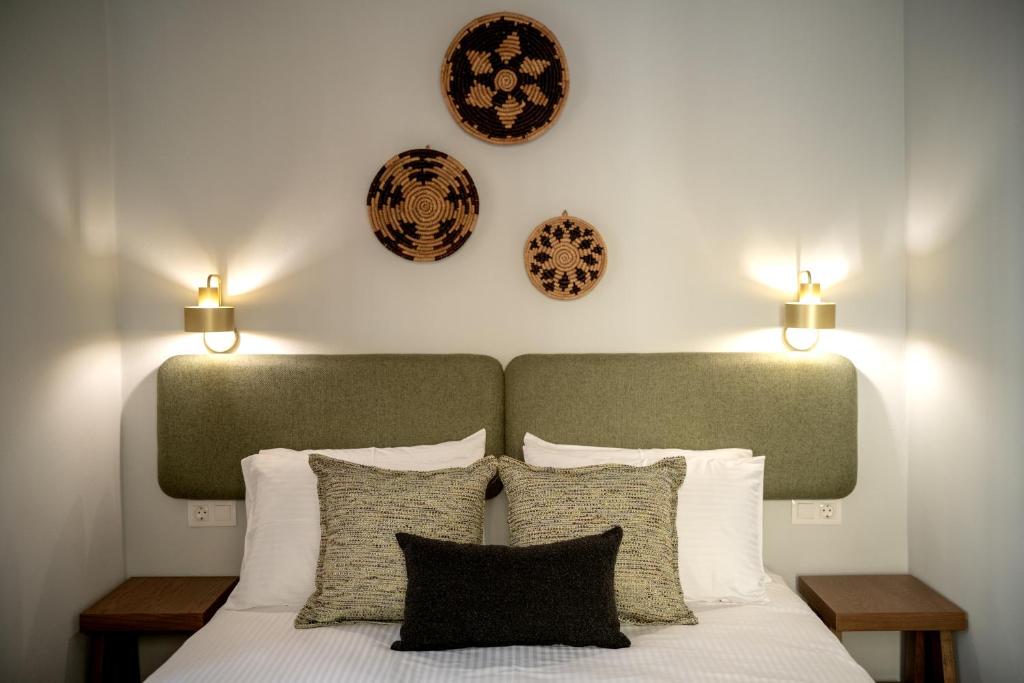 a bedroom with a bed with pillows and clocks on the wall at Eva's paradise Syros in Ermoupoli