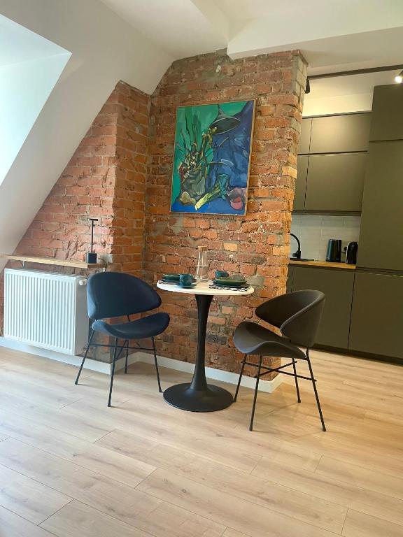 a table and chairs in a room with a brick wall at Szmaragdowa Sowa in Wałbrzych