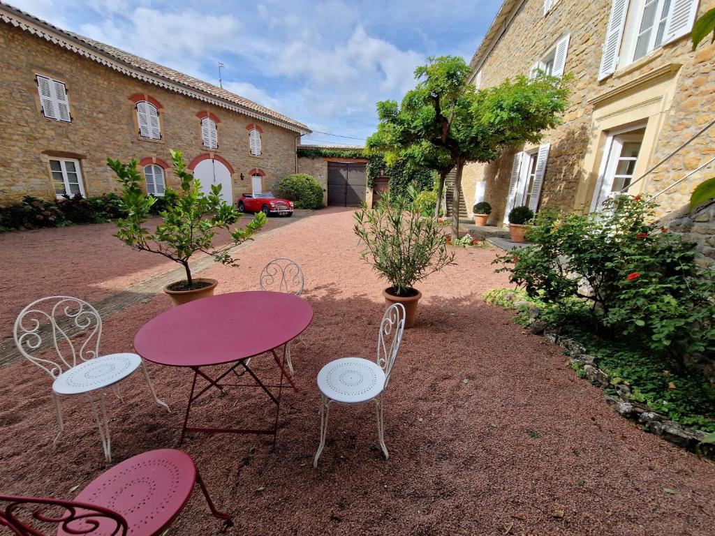 une table et des chaises roses dans une cour dans l'établissement DOMAINE DES FRANCHISES - Beaujolais Village - Charme et authenticité au cœur des Pierres dorées, à Denicé