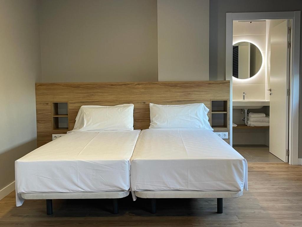 a bed with white sheets and pillows in a bedroom at Apartamentos CRUNIA - Estudios in A Coruña