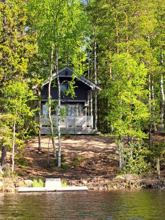 a cabin in the woods next to a body of water at Pieni Katajaranta in Karvonen