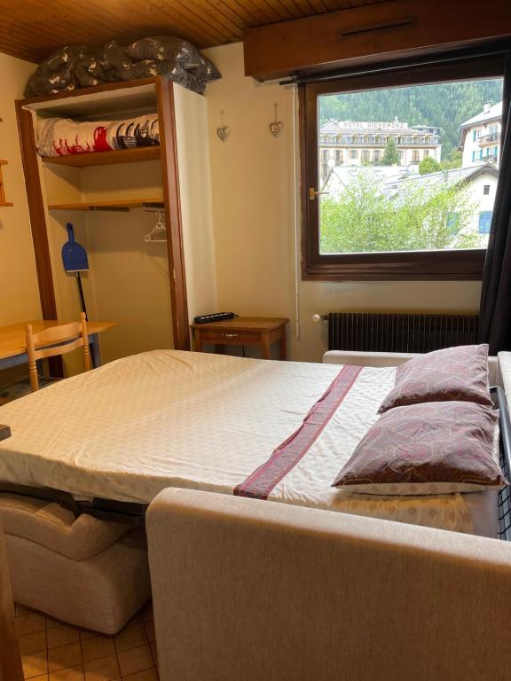 un grand lit dans une chambre avec une fenêtre dans l'établissement Studio meublé bon emplacement, à Chamonix-Mont-Blanc