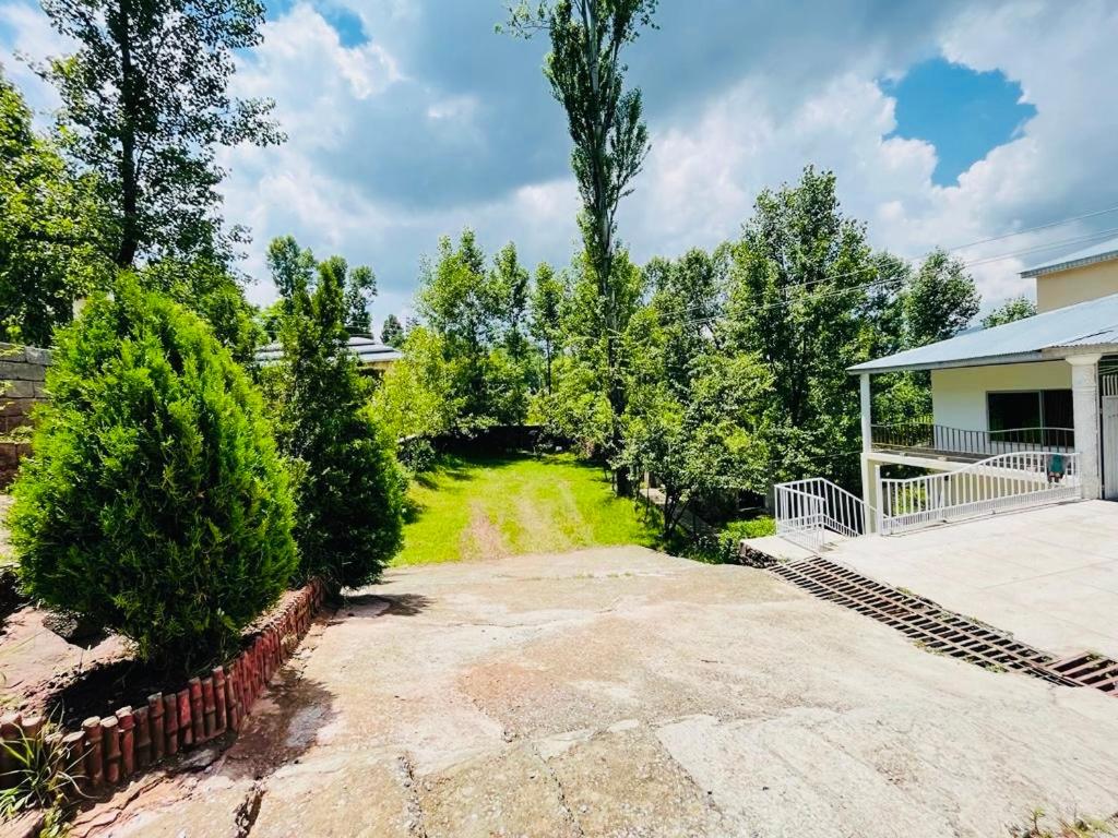 an image of a yard with trees and a house at Bhurban Lodges in Murree