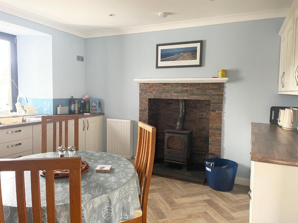a kitchen with a table and a brick fireplace at Oldshorecroft in Sheigra