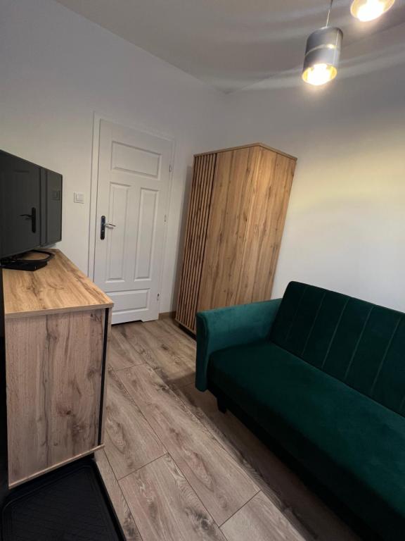 Una sala de estar con un sofá verde y un televisor. en Pretty Room Centrum, en Suwałki