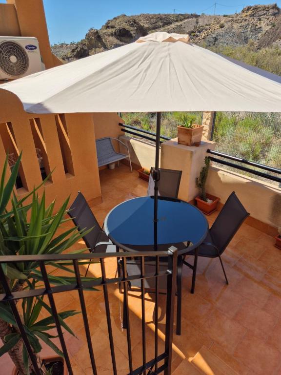 a table and chairs with an umbrella on a balcony at S&H La Malcriada in San Juan de los Terreros