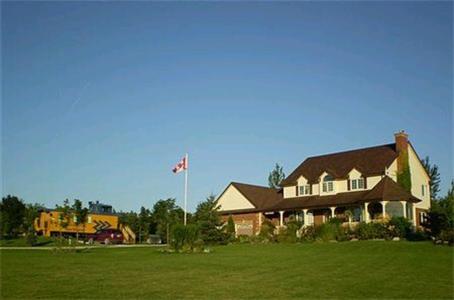 uma casa grande com uma bandeira num campo em Clearview Station & Caboose B&B em Creemore