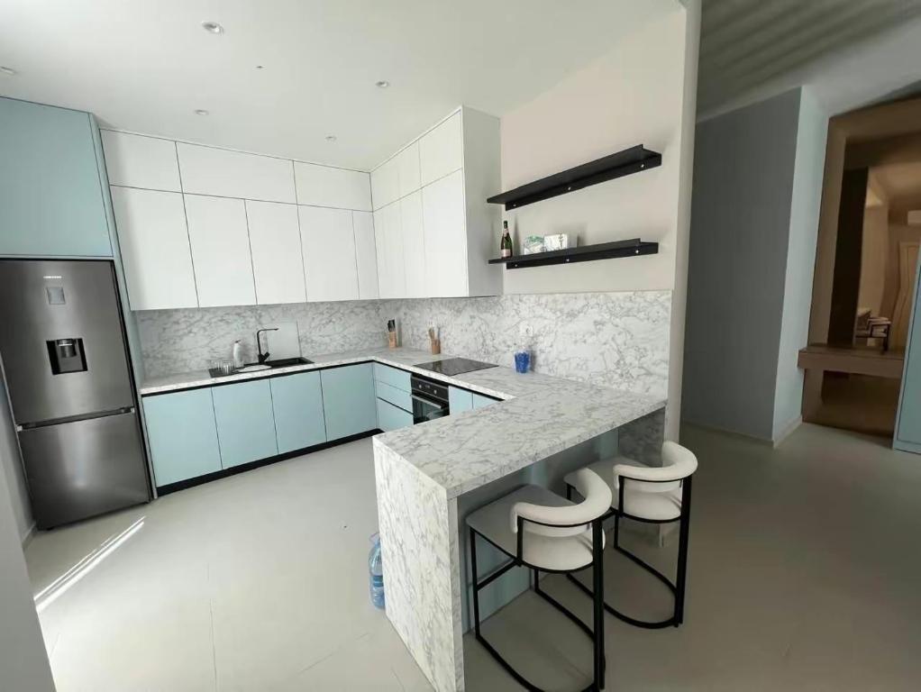 德尔米Green coast villa136 Palase的厨房配有白色橱柜、柜台和凳子