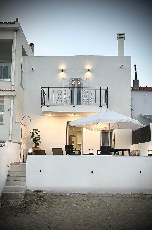 a white house with a table and an umbrella at Seaside Luxury Komi Beach Villa in Kómi