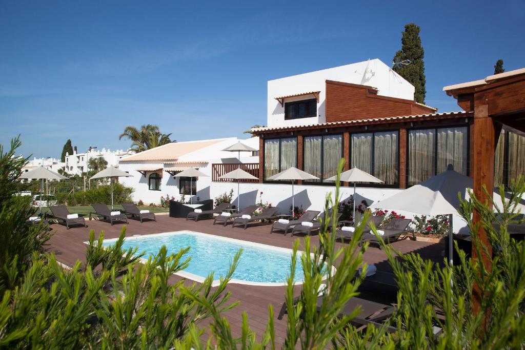 a resort with a swimming pool with chairs and umbrellas at Sao Rafael Holidays in Albufeira