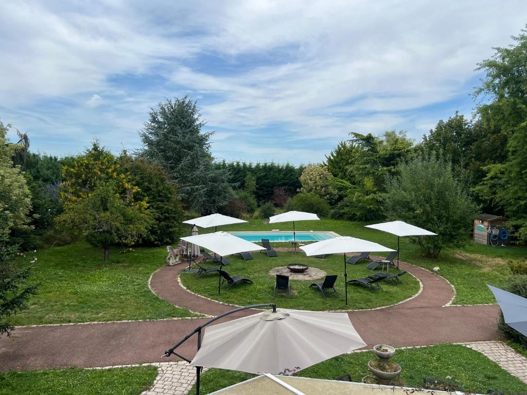 a group of tables and umbrellas in a park at La clé des champs - Les Grais 1H10 de Paris in Bazoches-sur-le-Betz