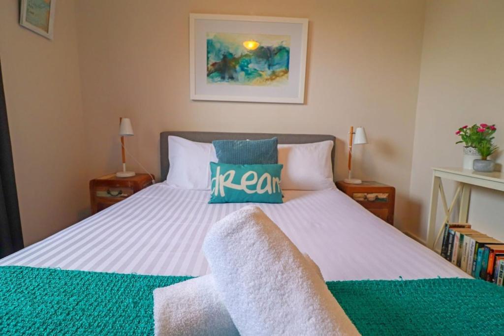 a bedroom with a bed with a green and white comforter at Beachside Cottage at Blacksmiths in Blacksmiths