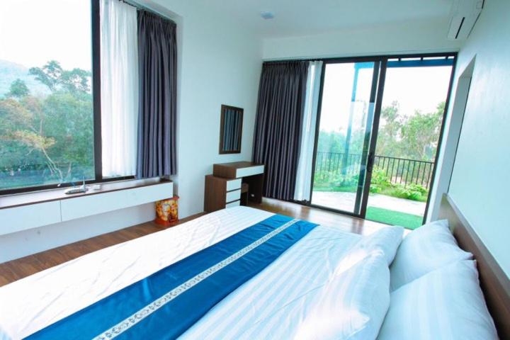 une chambre avec un grand lit et de grandes fenêtres dans l'établissement FLC Dai Lai Resort - SH315 Night Street 04PN, à Phúc Yên