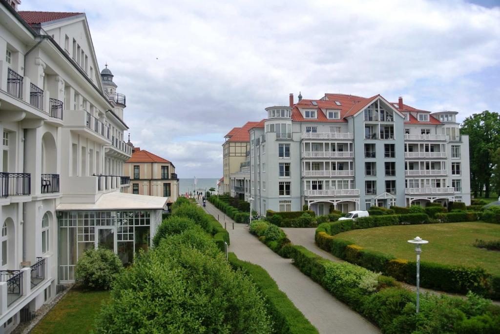 eine Reihe weißer Gebäude neben einer Straße in der Unterkunft Haus am Park Whg 02 in Kühlungsborn