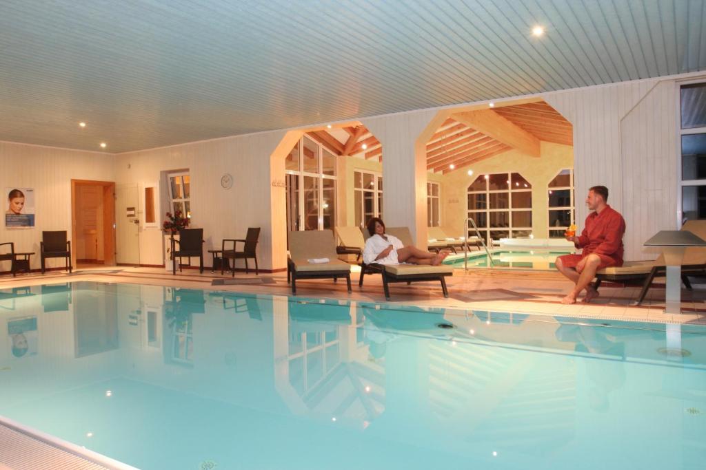 a group of people sitting around a swimming pool at Hotel Quellenhof in Bad Birnbach