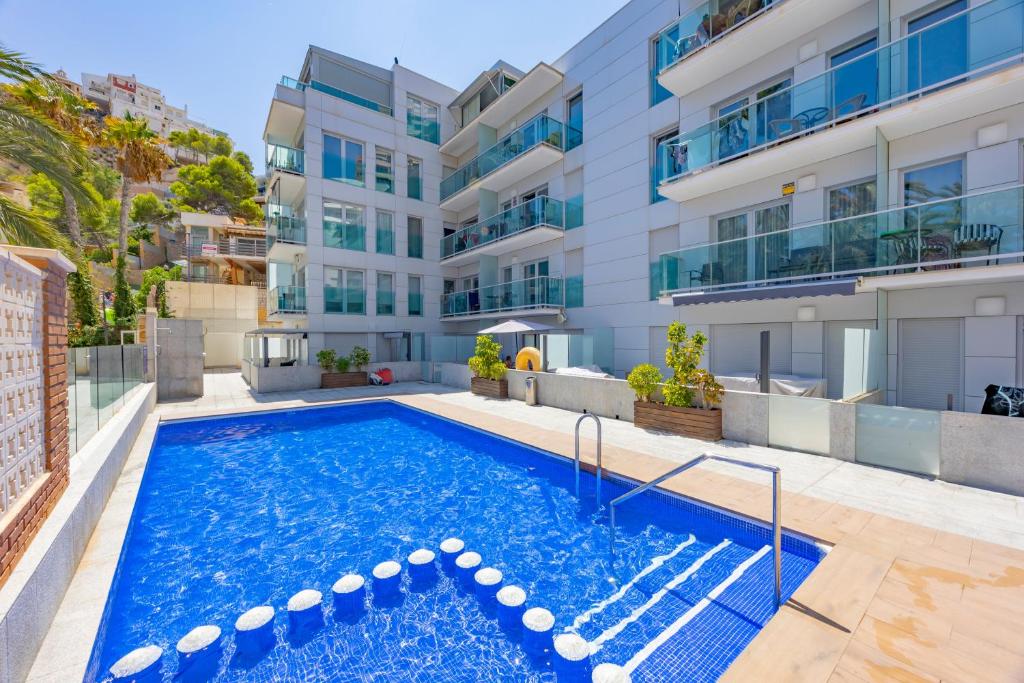 an apartment with a swimming pool in front of a building at Playa de Poniente in Benidorm
