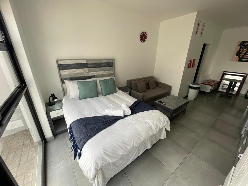 a bedroom with a large bed and a couch at Fischreiher Seaside Self Catering Studio Apartment in Swakopmund