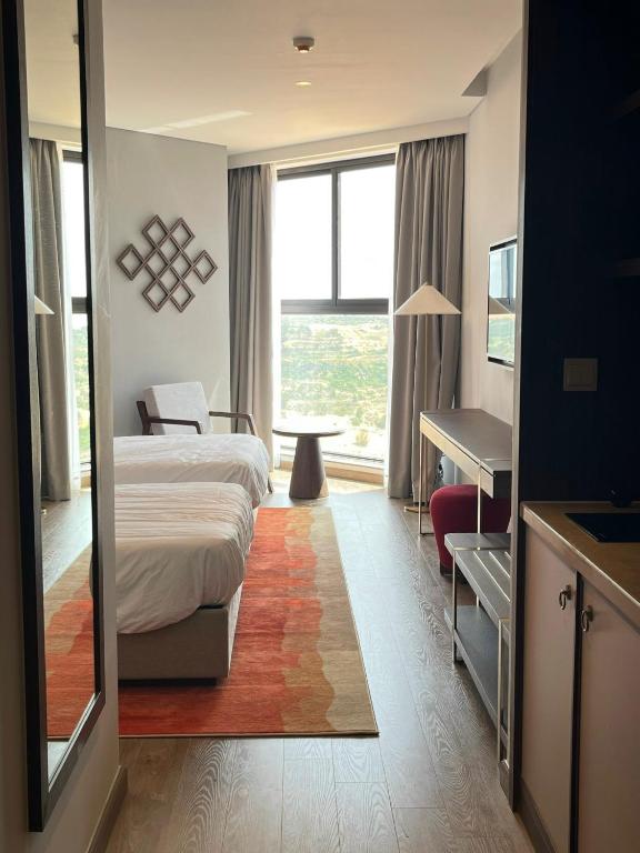 a hotel room with a bed and a large window at APEC MANDALA CHAMBAY Thanh La Home in Phan Thiet