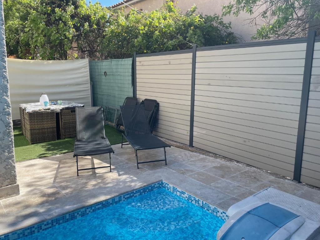 2 chaises et une piscine à côté d'une clôture dans l'établissement Appart avec Piscine privée proche Vélodrome et Metro, à Marseille