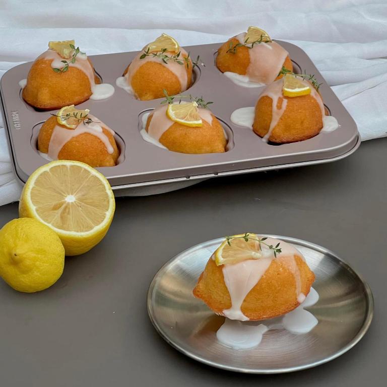 Small glazed lemon cakes are presented on trays and a metal plate.
