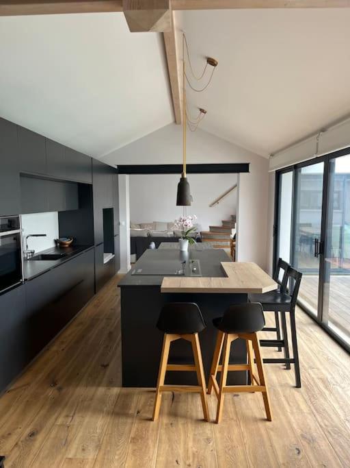 - une cuisine avec une grande île dotée de chaises et d'une table dans l'établissement Villa des Loriots, à Anglet