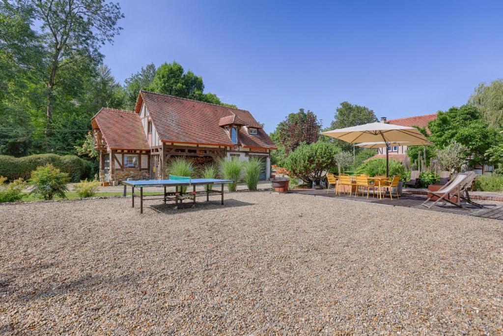 eine Terrasse mit Tisch und Stühlen und ein Gebäude in der Unterkunft Le Cottage à 10min de Disneyland Paris in Chalifert
