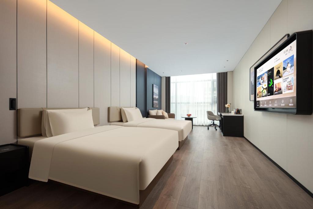 una camera d'albergo con due letti e una TV a schermo piatto di Atour Hotel Jieyang Banyan City Jieyang House a Jieyang