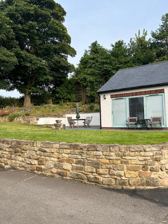 a stone wall in front of a house with a patio at Sharpley Hall Garden Studio not far from Seaham Beach offering Quiet Private Stay with Secure Parking in Seaham