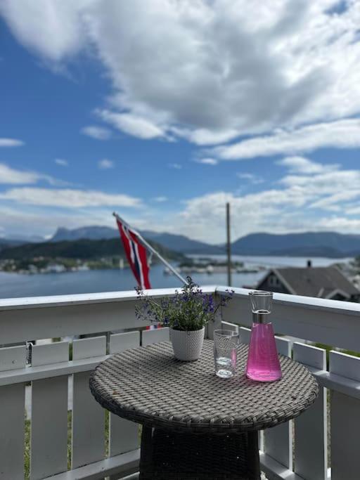 a table with a vase of flowers and an umbrella on a balcony at Hus med panorama utsikt in Måløy