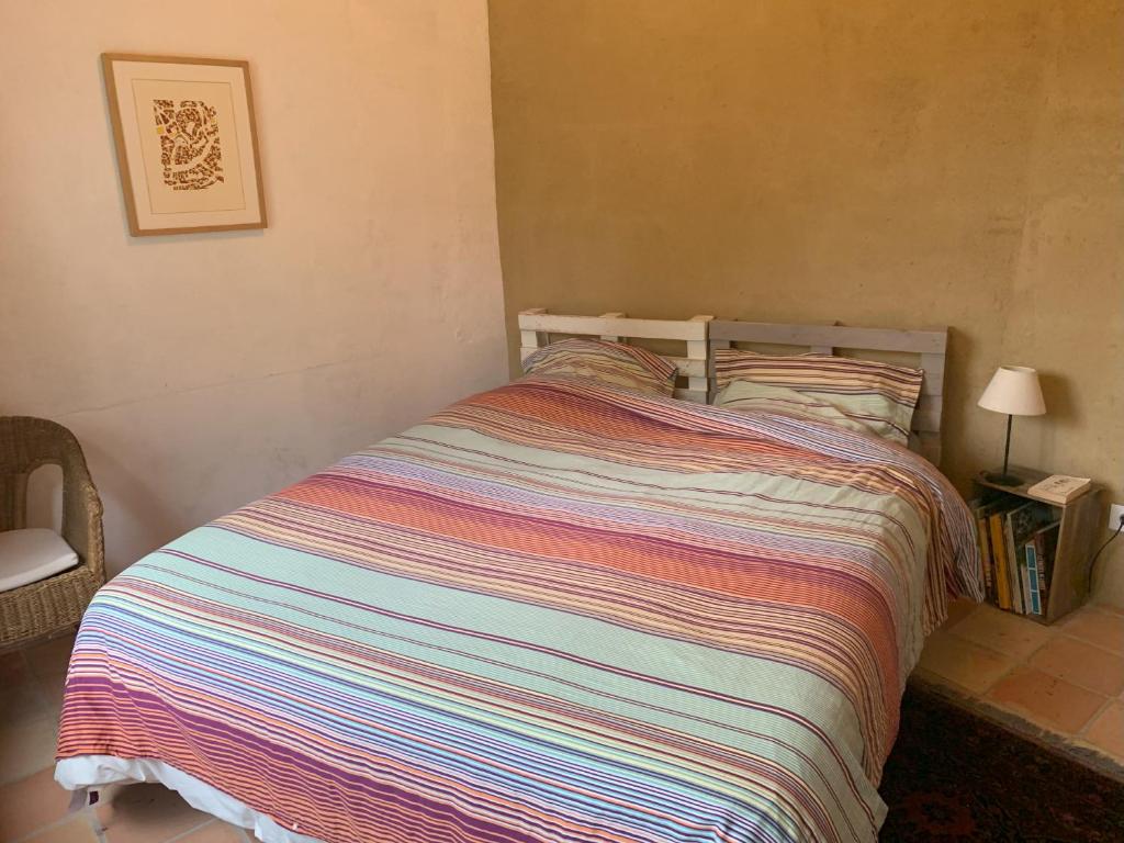 - un lit avec une couette colorée à rayures dans une chambre dans l'établissement Chambre d'hôte, à Monflanquin
