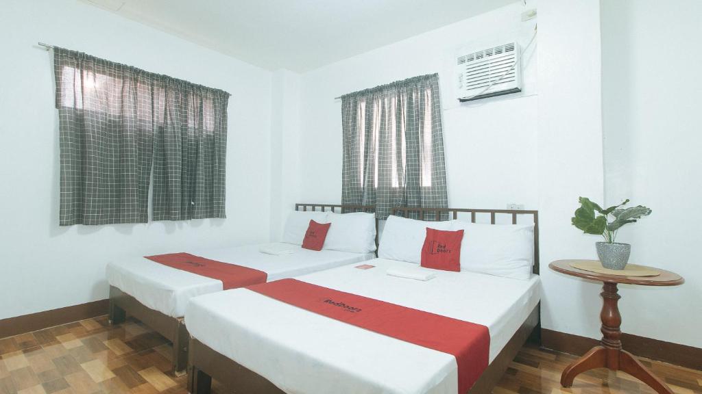 two beds in a room with white walls and windows at RedDoorz at Joel's Apartelle in Calaboso