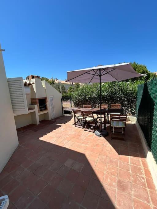 a patio with a table and an umbrella at Casa das Mélias in Vilamoura
